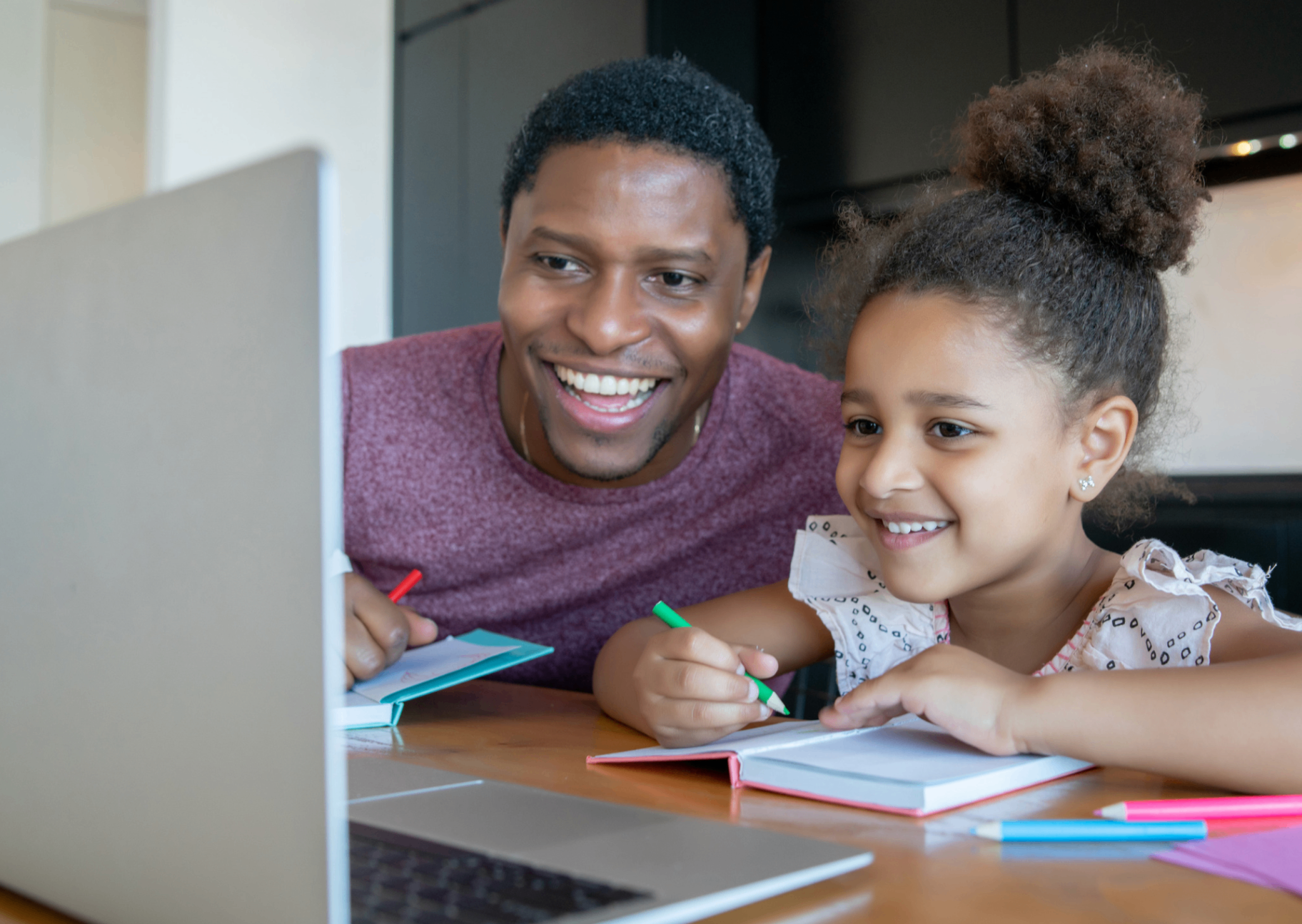 A parent and child smiling as they work on a lesson together.